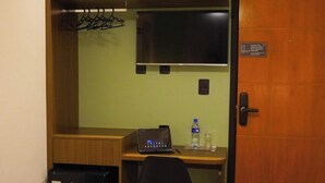 Habitación de hotel con escritorio, una silla, televisión, refrigerador pequeño y dos camas.