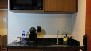 Una kitchenette compacta equipada con microondas, cafetera y lavavajillas.
