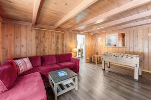 Ein gemütliches Zimmer mit Holzeinrichtung, einem roten Sofa, einem kleinen Tisch und einem Kicker.