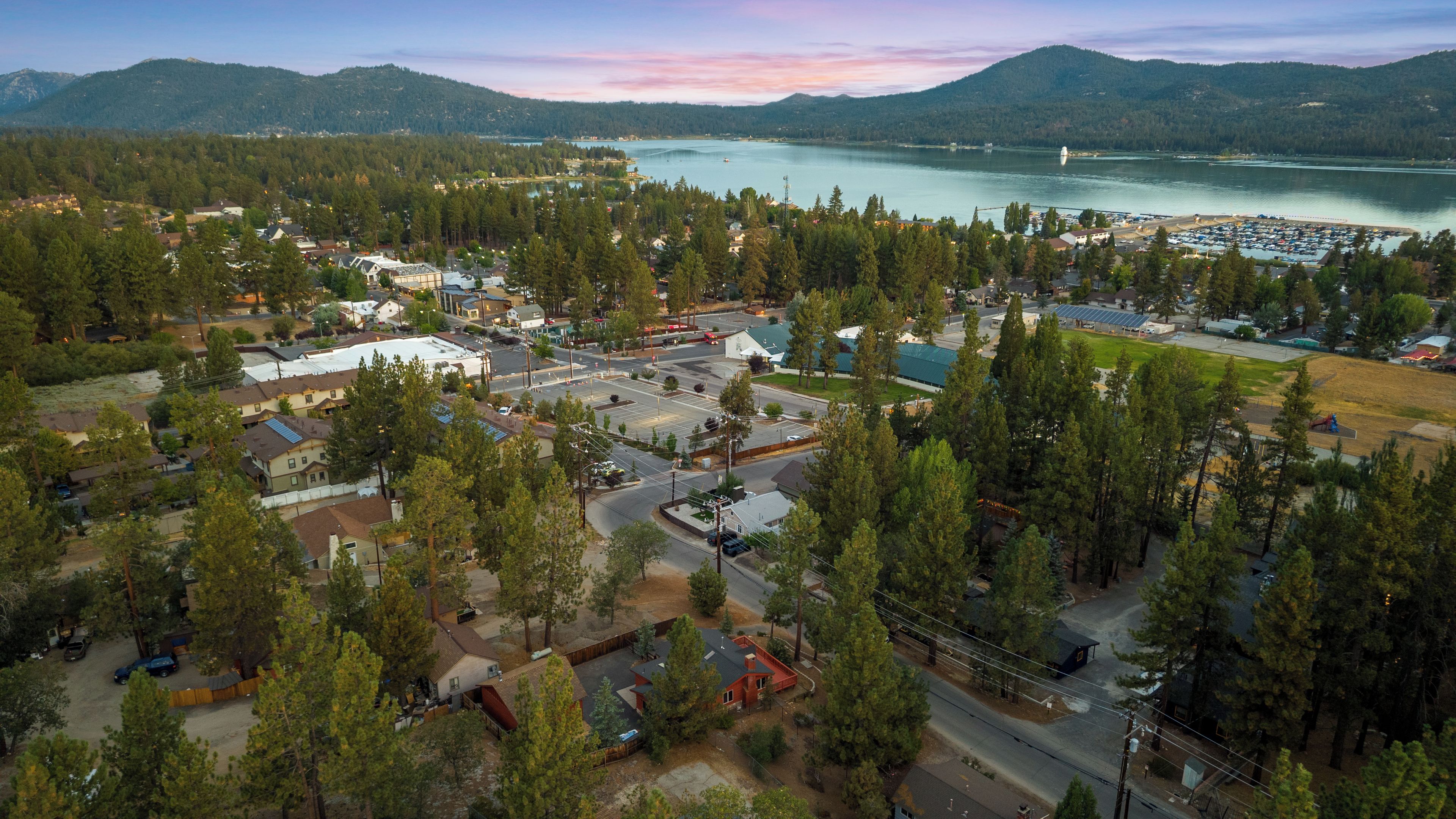 An aerial view of a residential area with houses, roads, and a large body of water in the background.