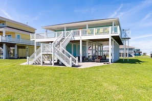 A two-story house with a covered patio, a staircase, and a small deck. - Lil Bit Salty 3 Bedroom Home (Port Bolivar)