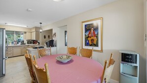A dining area with a round table, chairs, a water dispenser, and a poster on the wall. - The Peacock Villa 5 Bedroom Home (Las Vegas)