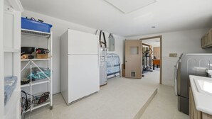 A compact kitchen with a refrigerator, a washing machine, and a sink. - The Peacock Villa 5 Bedroom Home (Las Vegas)