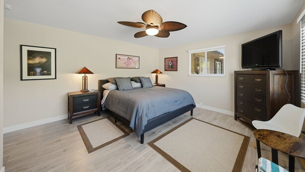 A bedroom with a bed, nightstands, a dresser, a ceiling fan, and a TV. - The Peacock Villa 5 Bedroom Home (Las Vegas)