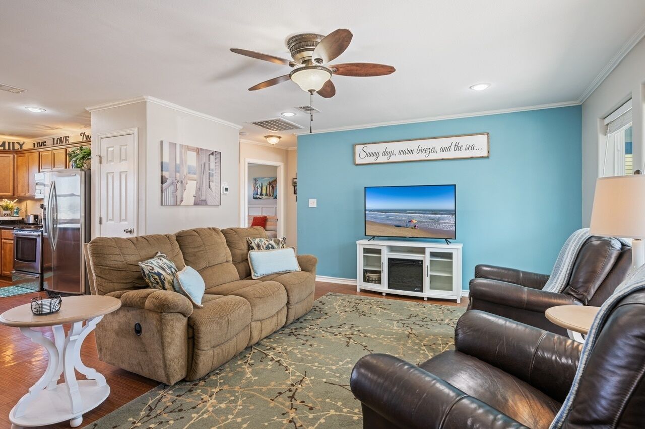 A living room with a sofa, a recliner, a television, and a ceiling fan.