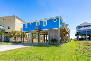 Un bâtiment à deux étages, à la façade bleue, doté d’un patio couvert et d’une pelouse verdoyante.