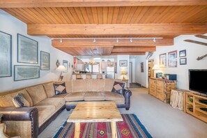 A living room with a wooden ceiling, a sofa, a coffee table, and a television. - Riverside Condos B101 2 Bedroom Condo (Telluride)