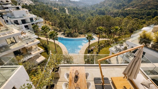 Un resort moderno con piscina, area salotto esterna e vista sulla foresta circostante.