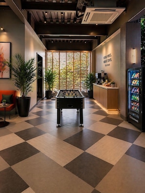 A hotel lobby with a foosball table, a vending machine, and a wall with a vertical garden. - Click Hotels Lite Chakan (Rajgurunagar)