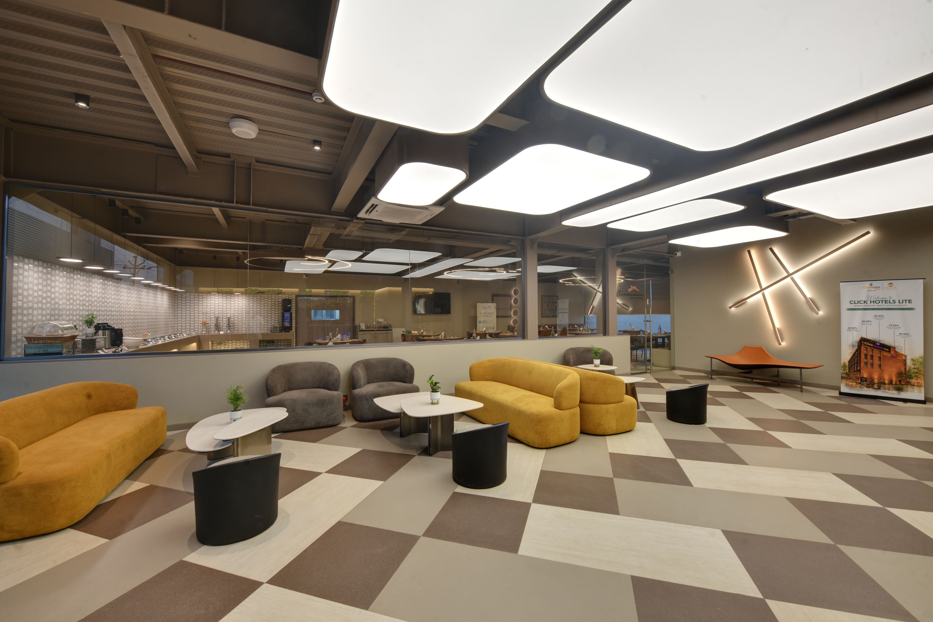 A modern hotel lobby with a check-in counter, seating area, and a large poster.