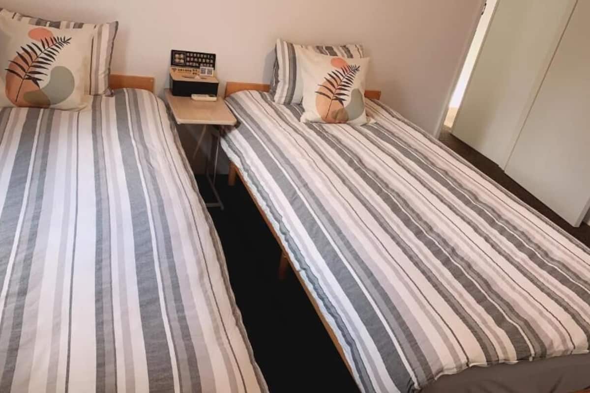 A twin room with two beds, a nightstand, and a small table.