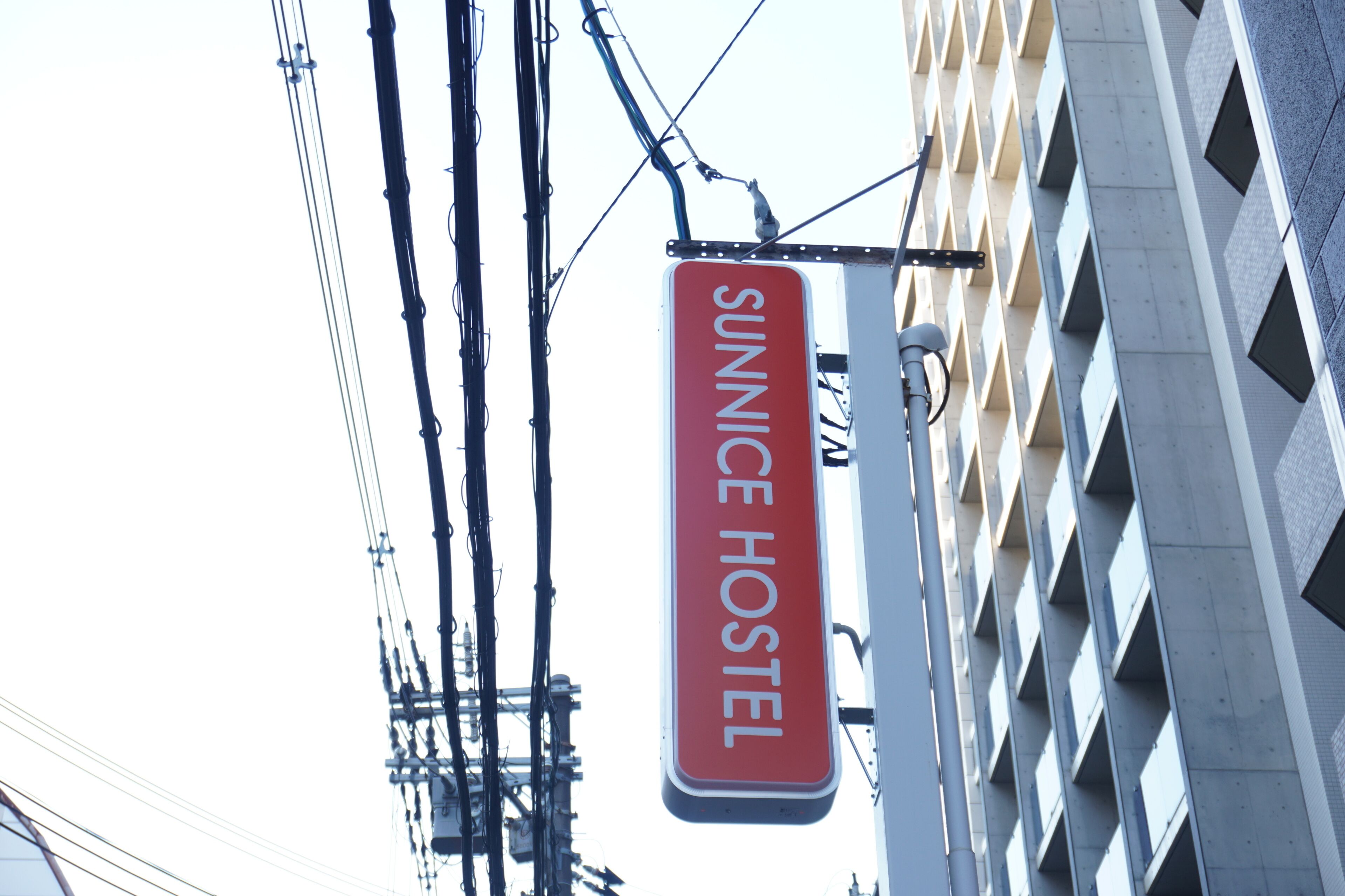 Ein Schild mit der Aufschrift 'SUNNICE HOSTEL' vor einem modernen Gebäude.