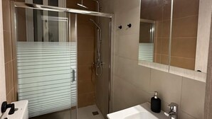 A bathroom with a shower, toilet, sink, and mirror. - Loutra Suites Spring Breeze Studio (Corinth)