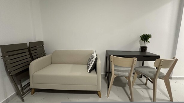 A room with a sofa, two chairs, a small table with a plant, and a radiator. - Loutra Suites Spring Breeze Studio (Corinth)