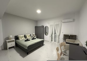 A bedroom with a bed, nightstands, a wardrobe, a mirror, a chair, and a desk. - Loutra Suites Spring Breeze Studio (Corinth)