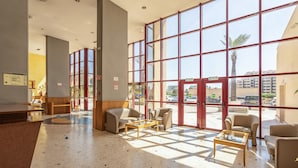 A spacious lobby with large windows, a reception desk, and several seating areas. - Apartment 'Praia Azul Ocean View' with Sea View, Wi-Fi and Air Conditioning (Portimão)