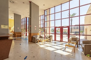 A spacious lobby with large windows, a reception desk, and several seating areas. - Apartment 'Praia Azul Ocean View' with Sea View, Wi-Fi and Air Conditioning (Portimão)