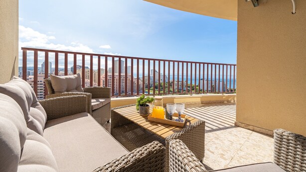 A balcony with wicker furniture, a tray with a drink, and a city view. - Apartment 'Praia Azul Ocean View' with Sea View, Wi-Fi and Air Conditioning (Portimão)