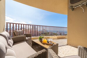 A balcony with wicker furniture, a tray with a drink, and a city view. - Apartment 'Praia Azul Ocean View' with Sea View, Wi-Fi and Air Conditioning (Portimão)
