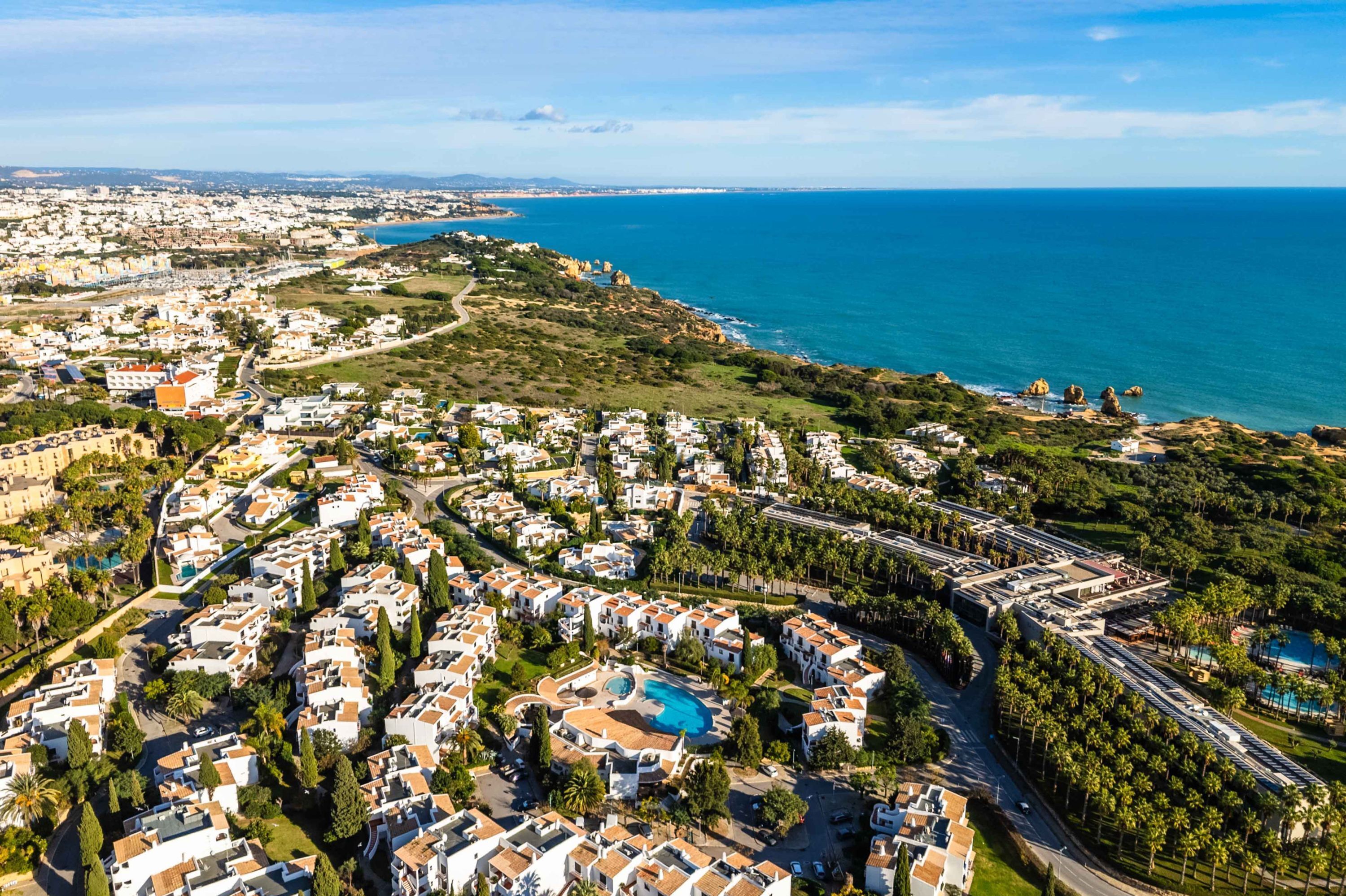 A coastal residential area with houses, a swimming pool, and a road.