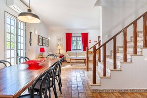 A dining area with a wooden table and chairs, a red lamp, and a staircase with patterned steps. - Casa das Conchas V4 Praia da Coelha (Albufeira)