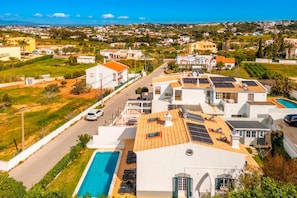 A residential area with houses, a swimming pool, and solar panels on rooftops. - Casa das Conchas V4 Praia da Coelha (Albufeira)
