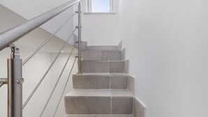 Un escalier avec une rampe métallique et une fenêtre en haut.
