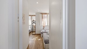 Un couloir étroit mène à une chambre à coucher qui contient un lit, une table de chevet et une armoire.