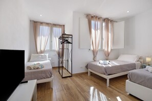 Ein Hotelzimmer mit zwei Betten, einem Fernseher, einem Kleiderschrank und einem Spiegel.