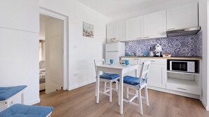 Une cuisine compacte avec des meubles blancs, un four à micro-ondes et un pare-feu bleu à motifs.