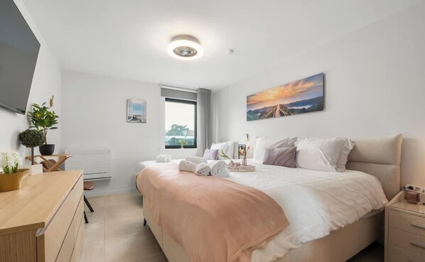 Ein modernes Hotelzimmer mit einem großen Bett, einem Schreibtisch, einem Stuhl, einem Fenster mit Blick und einem Bild an der Wand.