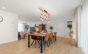 Ein moderner Essbereich mit einem Holztisch, schwarzen Stühlen und einer hängenden Leuchte.