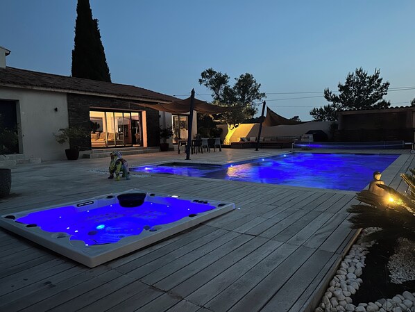A swimming pool with a hot tub, a patio area, and a building with large windows. - Stunning modern villa with views of Sainte Victoire, nestled between the sea and the mountains (Cabriès)