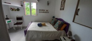 Una camera da letto con un letto, una scrivania, una sedia, una finestra e uno scaffale a parete.
