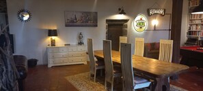 Un comedor con mesa y sillas de madera, un armario blanco, una lámpara, un cuadro y un cartel anunciando Murphy's Irish Stout.