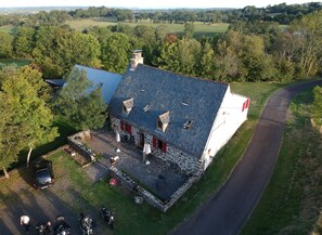 Un bâtiment en pierre doté d’un toit en pente, d’une allée pavée et d’un aménagement paysager environnant.