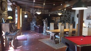 A billiards table, a fireplace, stone walls, and a dining area with chairs and a table. - Bed and Breakfast 'Roc' with Shared Terrace and Shared Garden (Saint-Bonnet-de-Salers)