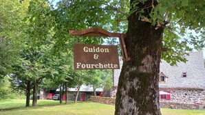 A rustic stone building with a sign reading 'Guidon & Fourchette.' - Bed and Breakfast 'Roc' with Shared Terrace and Shared Garden (Saint-Bonnet-de-Salers)