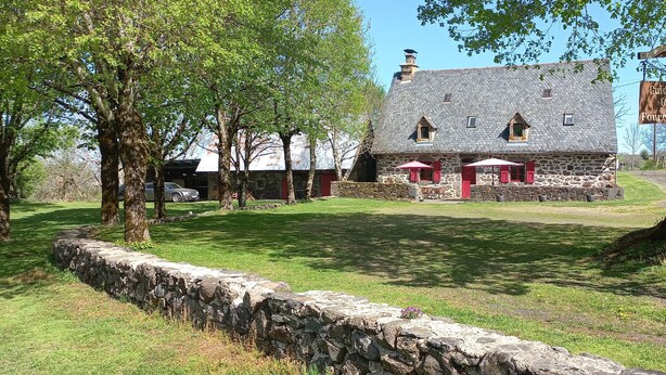 A stone building with a sign reading 'Guidon & Fourchette.' - Bed and Breakfast 'Roc' with Shared Terrace and Shared Garden (Saint-Bonnet-de-Salers)