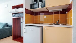 A compact kitchenette with a microwave, a small refrigerator, and a sink. - Small studio for 2 people, close to amenities (Agde)