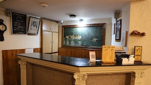 Un comptoir d’accueil surmonté d’un tableau encadré, une horloge au mur et un panneau avec un code QR.