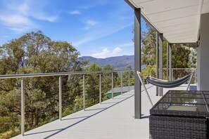 A balcony with a metal railing, a hammock, and a view of trees and mountains. - Eildon Valley Views - in the heart of the scenic Eildon Valley (Eildon)