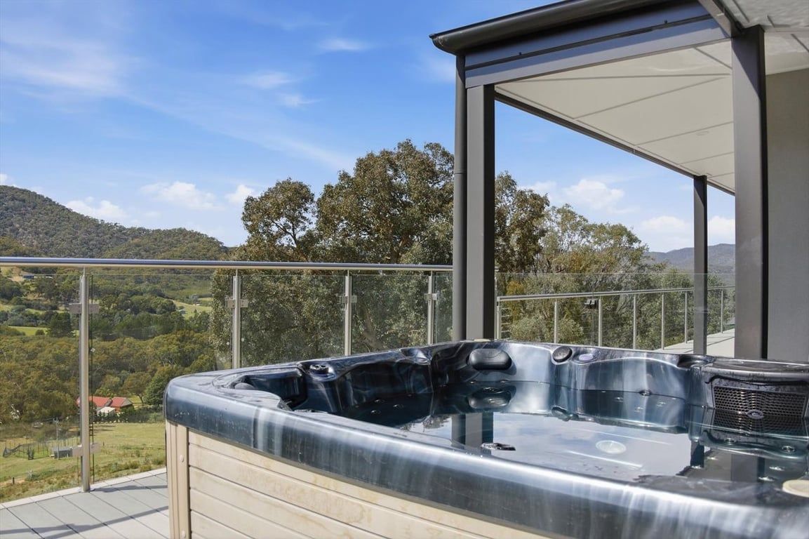 A hot tub on a balcony with a view of a hilly landscape.