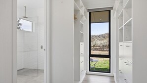 Ein modernes Interieur mit Glastür zur Dusche, einem großen Fenster mit Blick ins Freie und eingebauten Stauraumelementen.