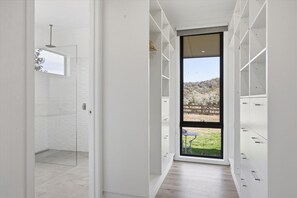 Ein modernes Interieur mit Glastür zur Dusche, einem großen Fenster mit Blick ins Freie und eingebauten Stauraumelementen.