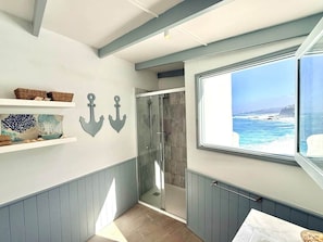 A bathroom with a shower, a window with a view of the sea, and decorative wall anchors. - Casa Riva, Private Villa with Pool Facing the Sea (Las Aguas)