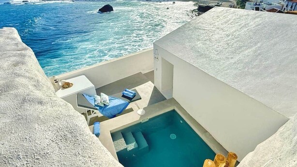 Ein Poolbereich mit Blick auf das Meer, eine Liege und ein kleiner Tisch.