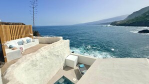 Eine Terrasse am Meer mit Pool, Sitzgelegenheit und Meerblick.