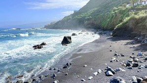 Ein Küstenstrand mit felsigem Gelände und freiem Blick auf den Ozean.