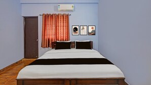 A bedroom with a bed, curtains, wall-mounted air conditioner, and three framed pictures. - Deluxe tad Homes (Sriperumbudur)